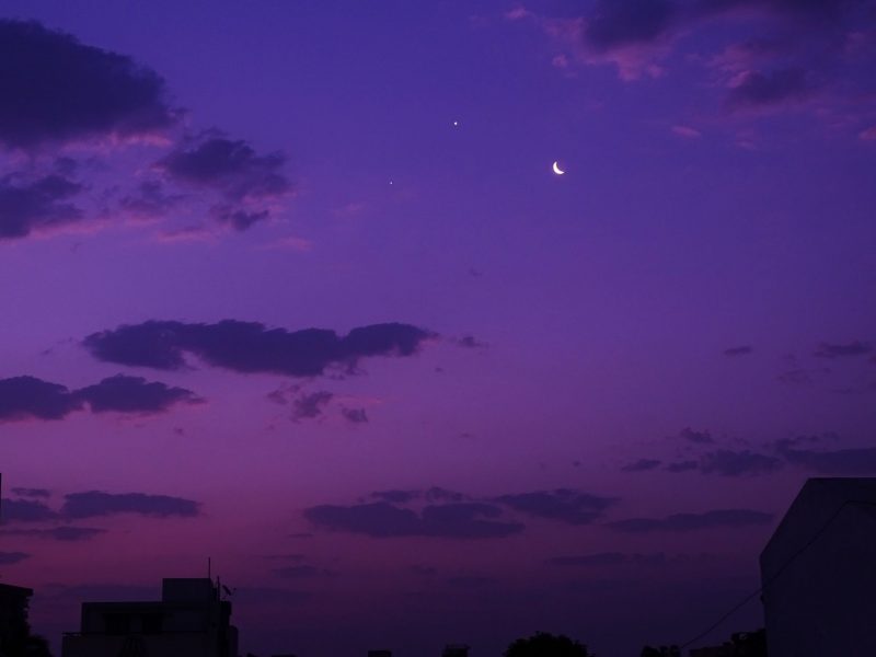 金星、木星与月牙在紫色的天空中和云彩构成了一幅美丽的风景画。作者：Pradnya Gharpure